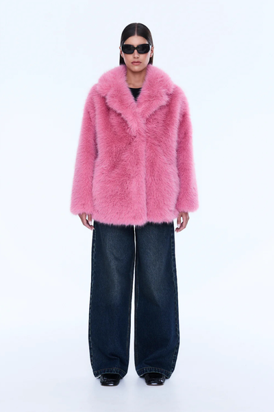 A full-length front view of the model standing with one hand casually placed inside the side pocket of the jacket, demonstrating the functional design elements and the effortless drape of the recycled polyester lining.