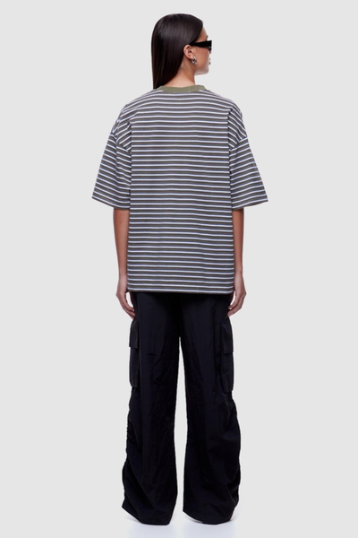 Studio rear view of a model showing the back fit and horizontal stripe pattern of an oversized short-sleeve t-shirt styled with black wide-leg pants.