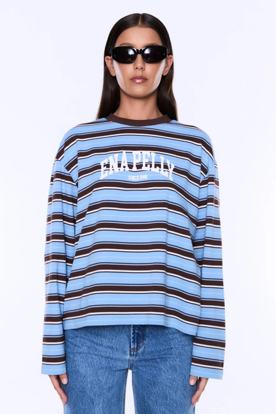 Front three-quarter studio portrait of a model wearing the ENA PELLY Maria Boxy Long Sleeve Tee in Blue/Brown Stripe featuring the collegiate ENA PELLY chest print.