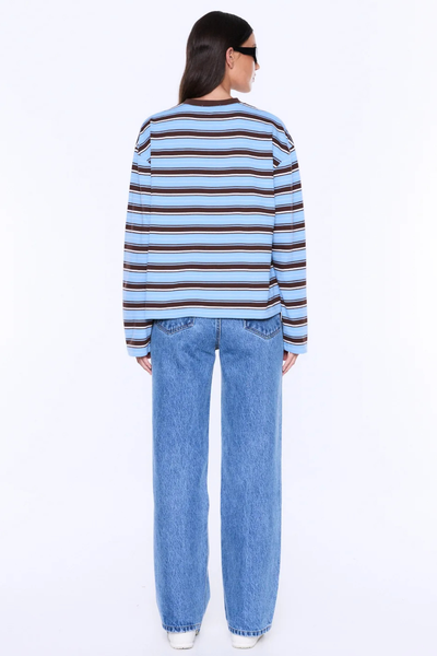 Rear view studio shot showing the back pattern and relaxed boxy silhouette of the ENA PELLY Maria Boxy Long Sleeve Tee in Blue/Brown Stripe styled with denim jeans.