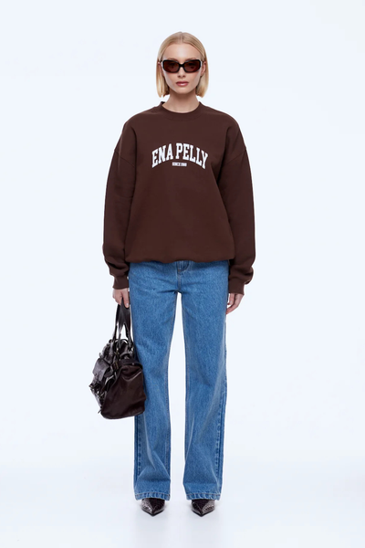 Rear full-length view showing the relaxed fit and plain back silhouette of the chocolate brown ENA PELLY Mila Oversized Sweater styled with blue denim jeans.