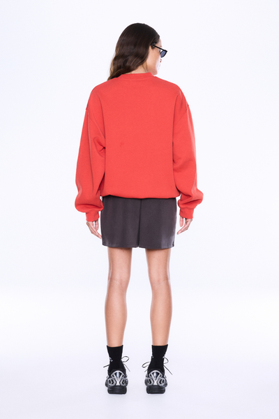 Full-length rear view of a model wearing the ENA PELLY Mila Oversized Sweater in Vintage Red, showing the clean back design and ribbed hem fit.