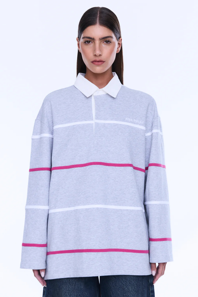 A cropped three-quarter front portrait focusing on the upper body, highlighting the placement of the subtle white embroidered brand name on the left chest, the clean lines of the white contrast polo collar, and the alternating pink and white sporty horizontal stripes.
