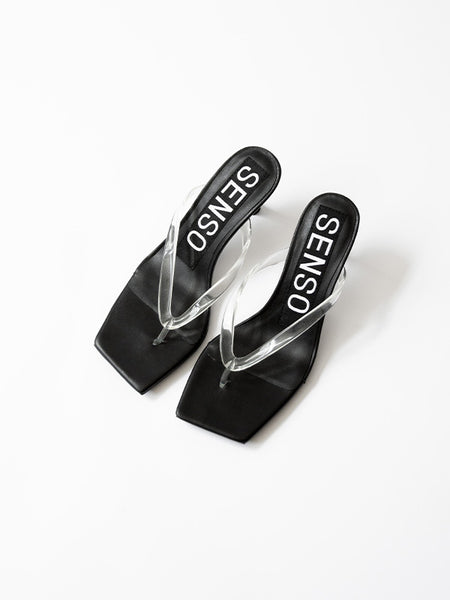 A direct, clean hero side profile studio shot of the Senso Enigma slip-on mule in Ebony, highlighting the smooth slope of the matte black leather upper and the curved 70mm sculptural heel block.