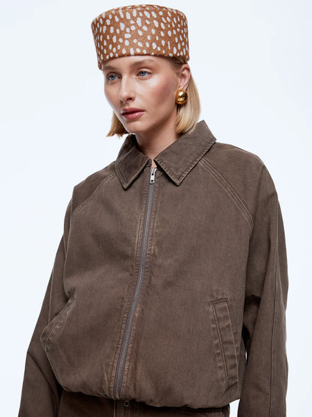An angled close-up studio shot detailing the upper torso of the ENA PELLY Billy Denim Bomber Jacket. The close-up showcases the rich texture of the mushroom-washed cotton denim, the functional front welt pocket, the metallic two-way zipper, and prominent collar tailoring.