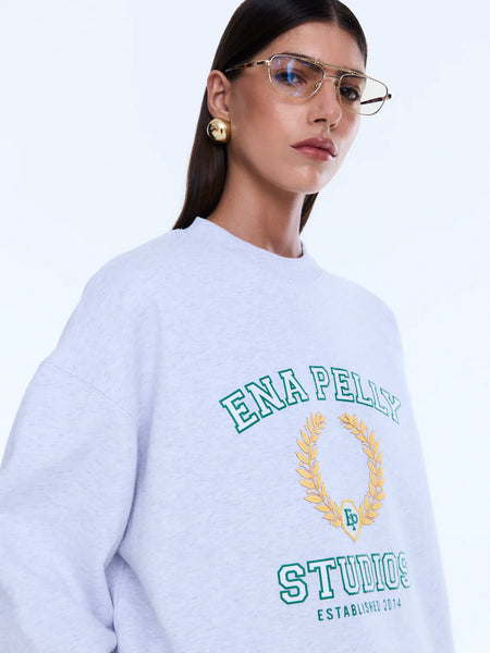 A close-up of the chest logo, showcasing the textured white bouclé lettering contrasted by the fine light yellow embroidered "Studios" script.