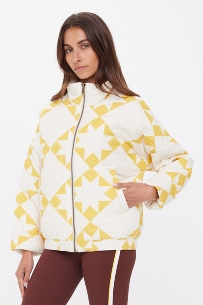 A three-quarter view of the golden sand star-print jacket, illustrating the cozy, insulated structure and functional front welt pockets.