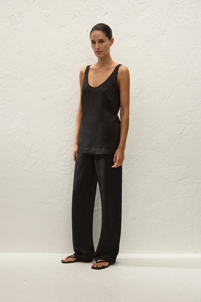 Full-length studio three-quarter front view of a model wearing a black viscose-blend sleeveless scoop-neck top paired with fluid black wide-leg trousers.