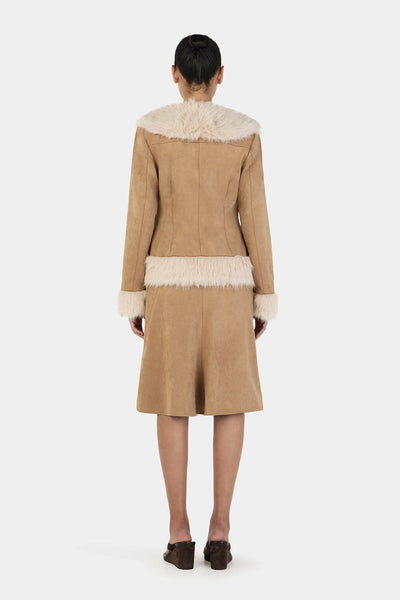 A rear-angle shot focusing on the lower half of the coat, illustrating the smooth drape of the fully lined tan suede body meeting the dense cream faux fur hemband.