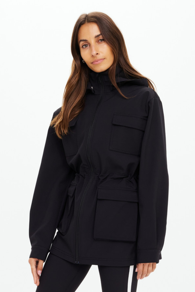 A cropped back-angle shot focusing on the drape of the anorak and the cinched elastic waist that provides a feminine shape to the utility piece.