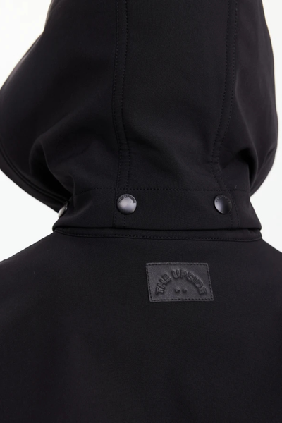 Macro view of the back neck, featuring "THE UPSIDE" rubberized logo patch and snap-button detailing on the detachable or adjustable hood.