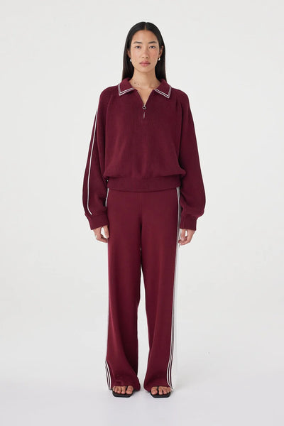 A full-length studio image featuring the model facing forward in the complete merlot and cream knit set, emphasizing a relaxed yet tailored look for loungewear or travel.