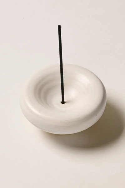 Studio shot of the Gentle Habits Vessel Incense Holder in Cream with a single black incense stick placed upright in the center opening on a neutral off-white surface.