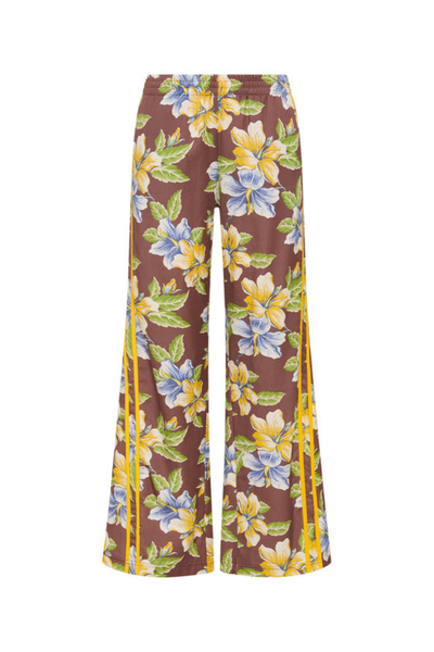 A low-rise botanical pants styled with a chocolate brown tank, emphasizing the "vintage ease" and vacation-ready aesthetic of the collection.