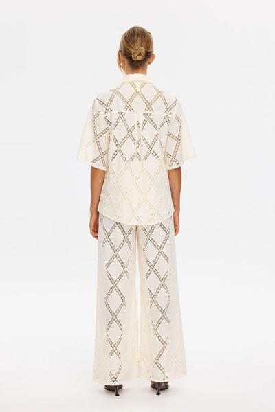 Back view of a model wearing the short-sleeve KIVARI Izzy Shirt in Cream showing the relaxed fit and continuous diamond lace paneling.
