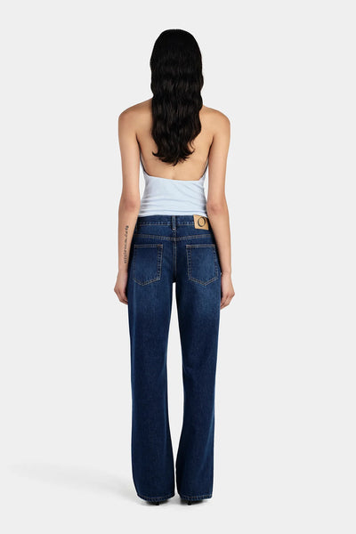 Studio rear full-length view of a model wearing dark blue jeans and a sky blue halter top featuring an open back design.