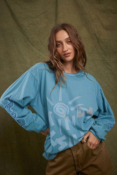 Medium studio shot of a model wearing the relaxed-fit Kinga Csilla Paper Sun Roses Tee in Blue paired with khaki denim shorts.