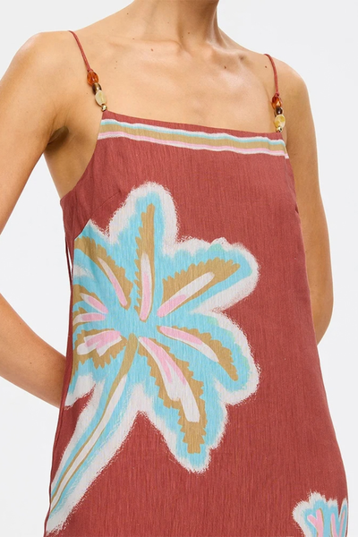 Close-up studio shot focusing on the straight neckline, bust darts, decorative bead detailing on the thin shoulder straps, and the aqua and ochre botanical placement print.