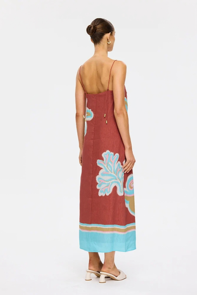 Studio rear three-quarter view of a model wearing the relaxed-fit maroon midi dress, showing the placement-print hem border and back strap ties.