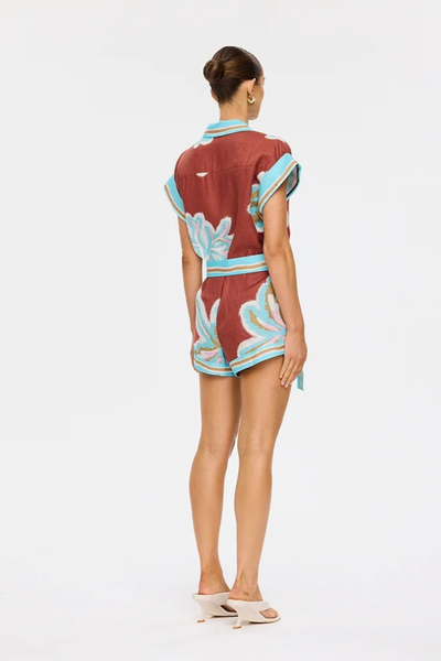 Studio rear three-quarter view of a model wearing the relaxed-fit printed playsuit, highlighting the shorts silhouette and matching tie belt.