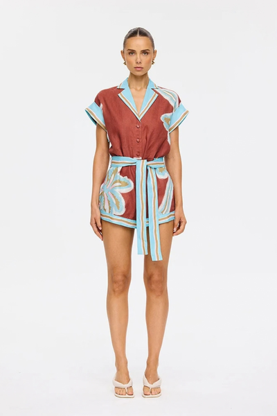 Studio front full-length view of a model wearing the button-down linen-cotton playsuit styled with a removable waist tie and strappy heels.
