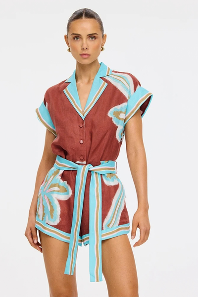 Studio front view of a model wearing the relaxed-fit playsuit, showcasing the Mediterranean tile-inspired border details and painterly motifs.