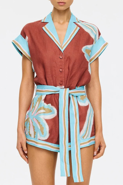 Studio close-up waist view highlighting the button placket, side pockets, and the tied fabric belt of the maroon and aqua playsuit.