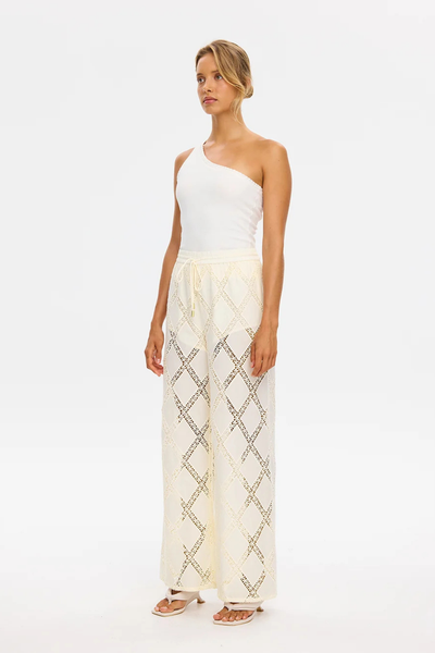 Studio full-length view of a model wearing the wide-leg KIVARI Izzy Pant in Cream paired with a white one-shoulder ribbed top.