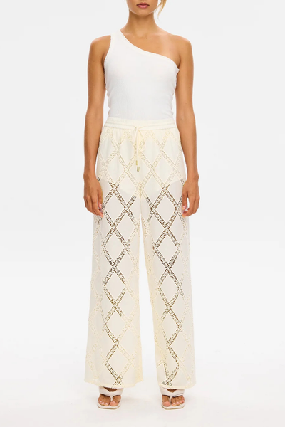 Studio front shot of a model wearing the KIVARI Izzy Pant in Cream and a white ribbed tank top, showing the relaxed wide-leg silhouette and boyleg lining.