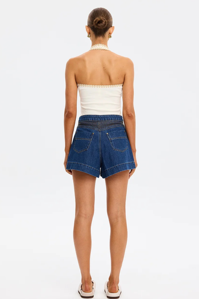 Full rear view of a model wearing the backless Kivari Rhea Halter Top in Cream, detailing the scalloped hand-crocheted border along the back band and halter neck.