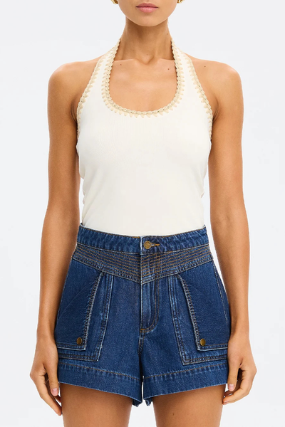 Cropped front view of a model showcasing the fitted silhouette and hand-crocheted halter neck trim of the cream Kivari Rhea Halter Top paired with structured dark denim shorts.