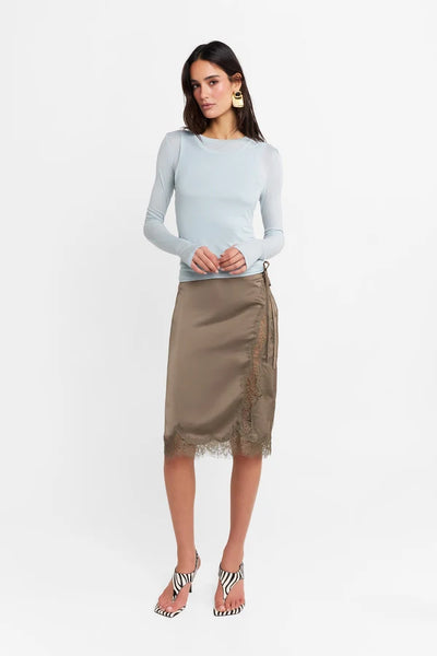Full-length studio front view of a model wearing the powder blue long-sleeve top paired with a taupe skirt and zebra-print heeled sandals.