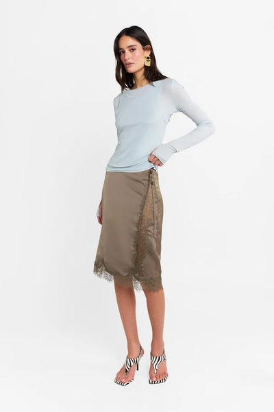 Studio three-quarter view of a model posing in the powder blue stretch-fabrication Kova top with thumb holes.