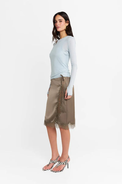 Studio side profile of a model wearing the powder blue long-sleeve top, showcasing the smooth stretch fabric and body-contouring fit.