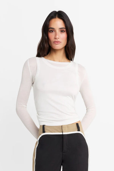Studio front portrait of a model wearing the white double-layer Kova top, highlighting the double scoop neckline and long sleeves.