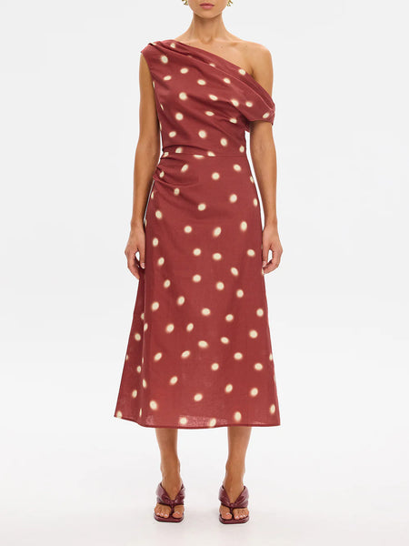 A three-quarter angle studio shot of a model showcasing the side profile and flattering fluid drape of the polka-dot linen-blend midi dress.