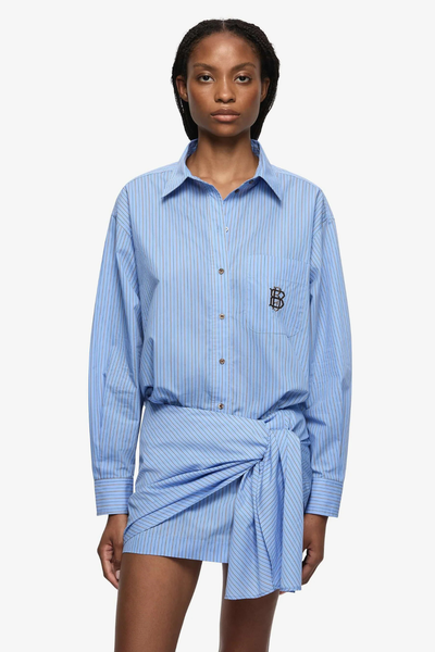 A wrap-style Linus Mini Skirt in Chambray Blue and white stripes, featuring a decorative side-seam tie and a clean mini length.