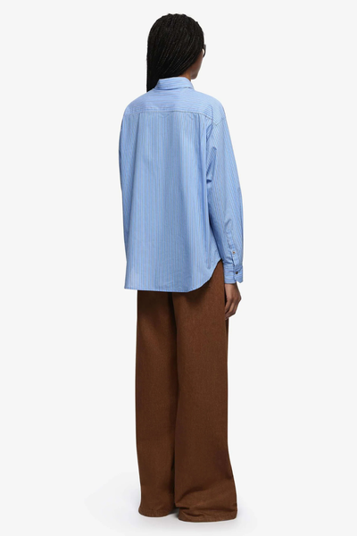 Rear view of the Linus Shirt in Chambray Blue Stripe, showcasing the generous oversized back panel and the straight-cut hemline.
