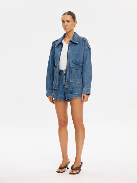 A waist-up studio layout shot focusing on the front design details of the open Rita Denim Jacket, highlighting the placement of the oversized front patch pockets and contrast topstitching.