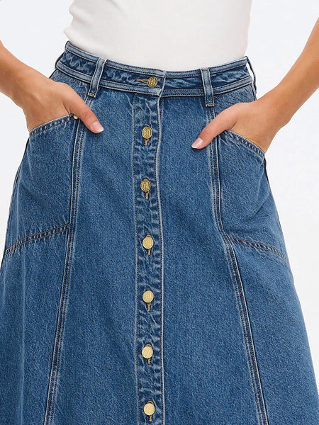 A close-up studio product shot detailing the high-rise waistband of the Rita Denim Skirt in Drift Blue, emphasizing the signature gold hardware buttons, intricate contrast topstitching, and subtle whiskering on the denim panels.