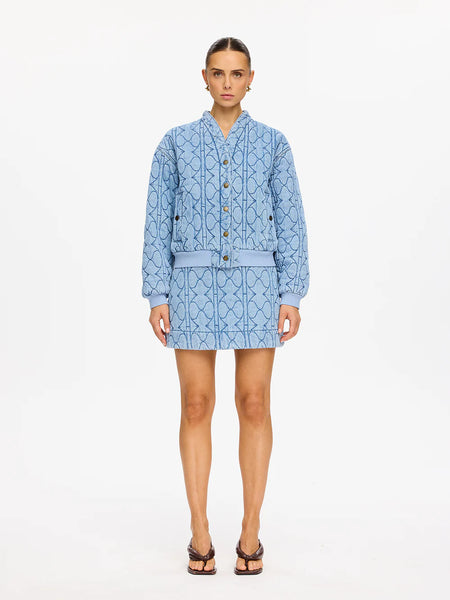 A full-length front studio shot of a model wearing the Kivari Joey Denim Jacket in Pale Stone, highlighting its oversized silhouette, signature wavy quilted texture, and snap button front closures.