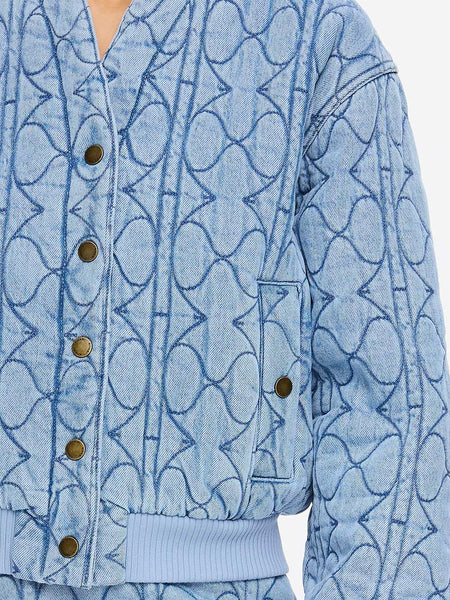 A detailed close-up shot of the front bodice, highlighting the textured ribbed detail hem, matching ribbed sleeve cuffs, and the metallic sheen of the signature logo snap buttons.