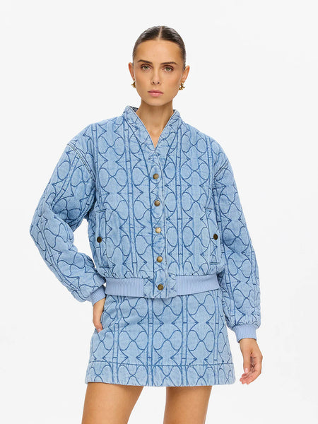 A close-up studio portrait focusing on the clean round collar and the unique, soft handfeel of the quilted pale stone fabric weave.