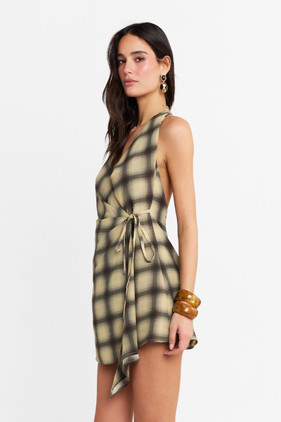 Side profile close-up of a model wearing the check mini dress, showcasing the wrap-around waist tie, chunky bracelets, and earrings.