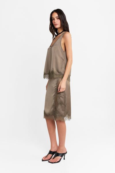 Full-length studio side profile view of a model wearing the matching satin tank top and skirt set in thyme, paired with black heels.