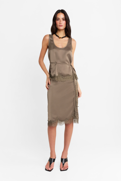 Full-length front studio view of a model wearing the matching satin Velune top and skirt set in thyme, styled with a thin waist tie, black necklace, and black heeled sandals.