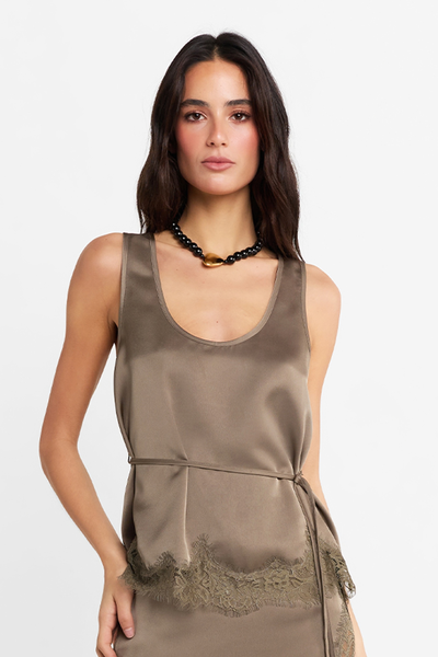Close-up front studio view of a model wearing the satin Velune Top in Thyme featuring a scoop neckline, thin waist tie, and lace hem, accessorized with a black beaded statement necklace.