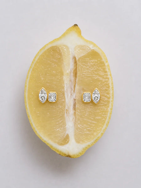 Creative still-life shot of the gold stud earrings placed flat on a freshly sliced yellow lemon.