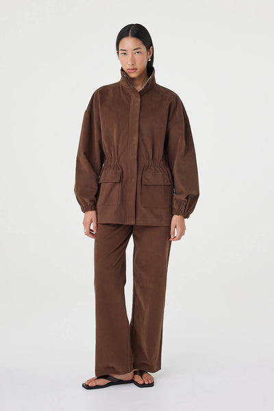 A full-length front studio view with the jacket zipped to the top, accentuating the minimal, refined finish of the center front concealed zipper and the symmetry of the front flap utility pockets.