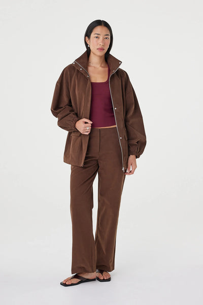 A full-length front studio shot showcasing the jacket styled open as an everyday outer layer. The model wears it over a contrasting plum-colored ribbed tank top to demonstrate ease of layering.